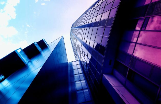 Low angle shot of modern skyscrapers with reflective glass facades and vibrant colors in an urban setting.